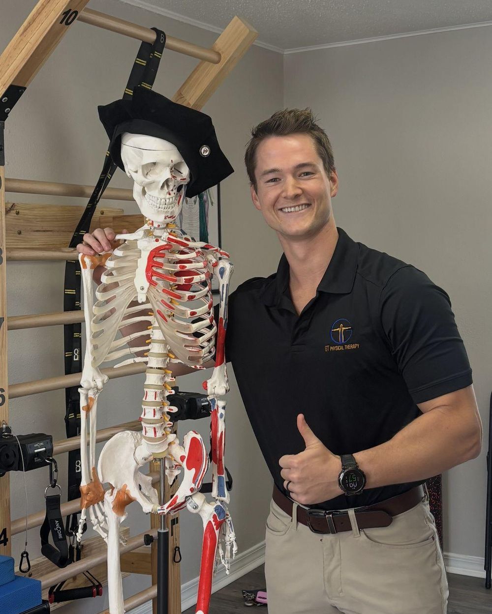 Dr. Austin Baskin standing in the clinic beside an anatomy skeleton