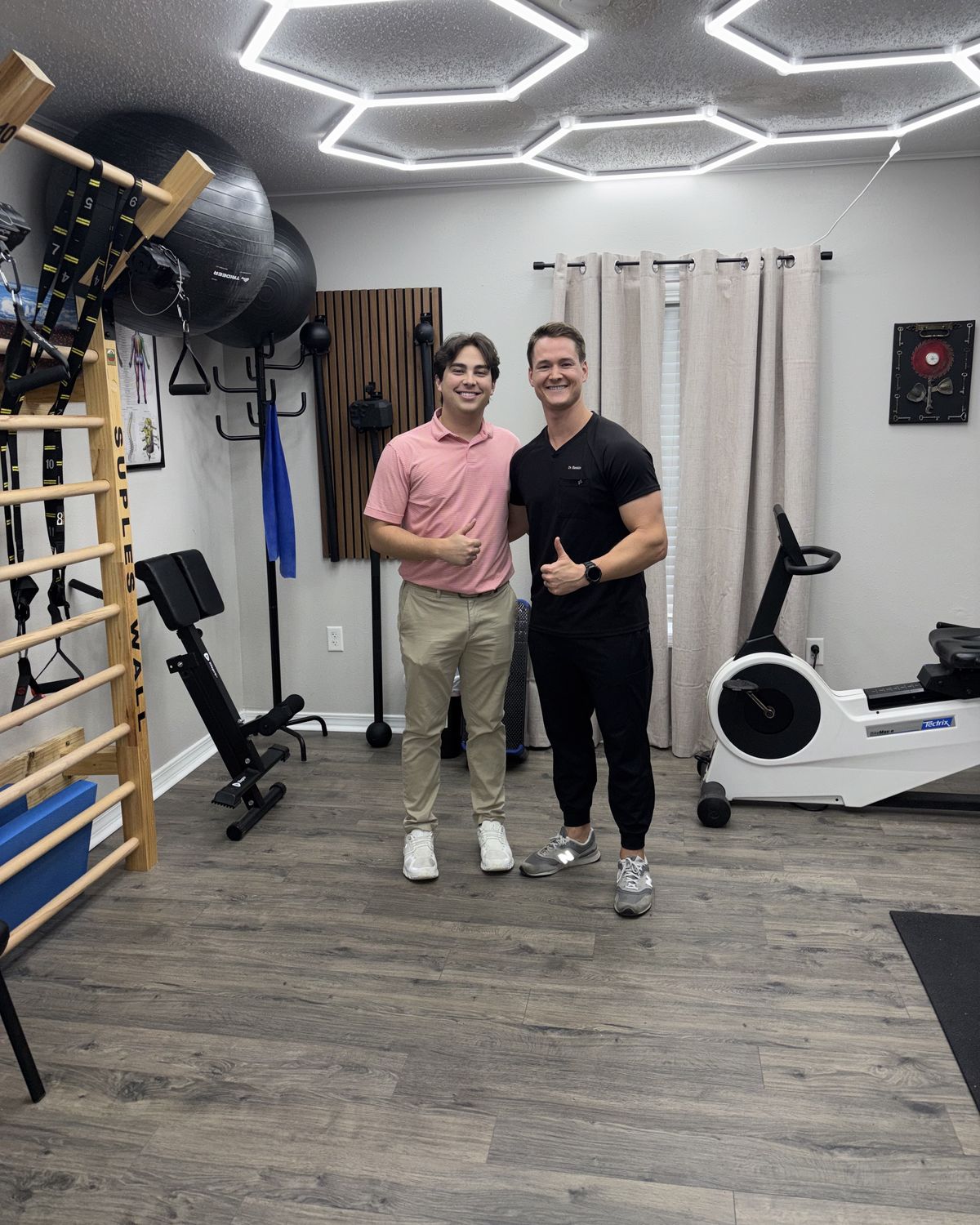 Dr. Baskin and a patient in the clinic's treatment gym, with a wall ladder and exercise equipment